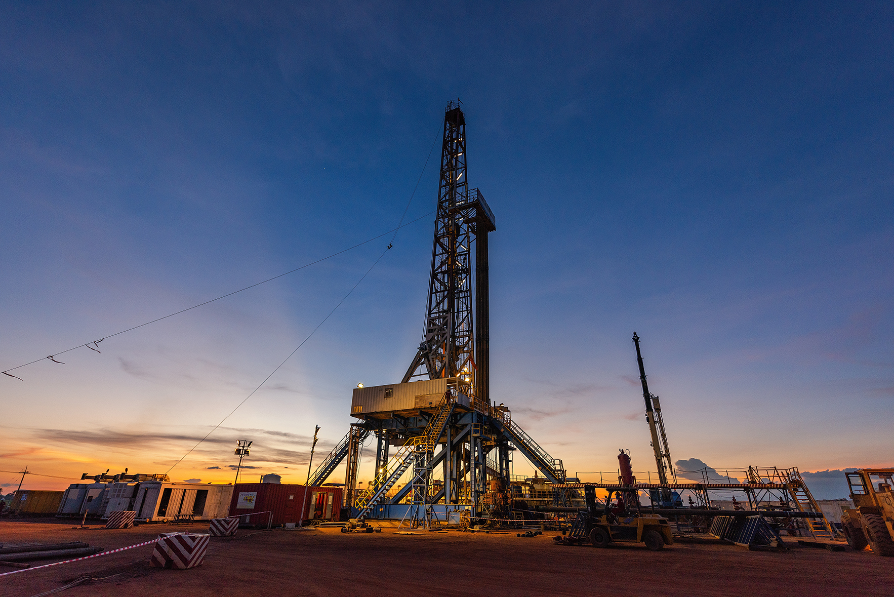 sunset view of an oil drilling operation on land