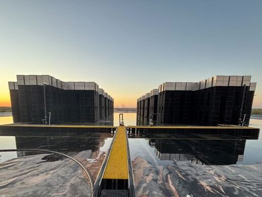 a view of two matrix towers at sunset, in a partially dried pond